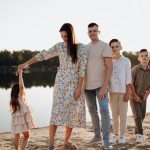 A family of five enjoys a serene lakeside vacation at sunset, capturing precious moments together.